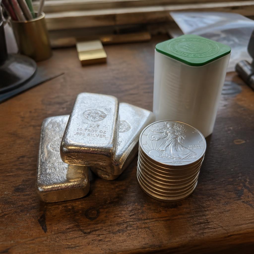 Hand-poured 10 oz silver bars and a stack of American Silver Eagle bullion coins on a shop counter
